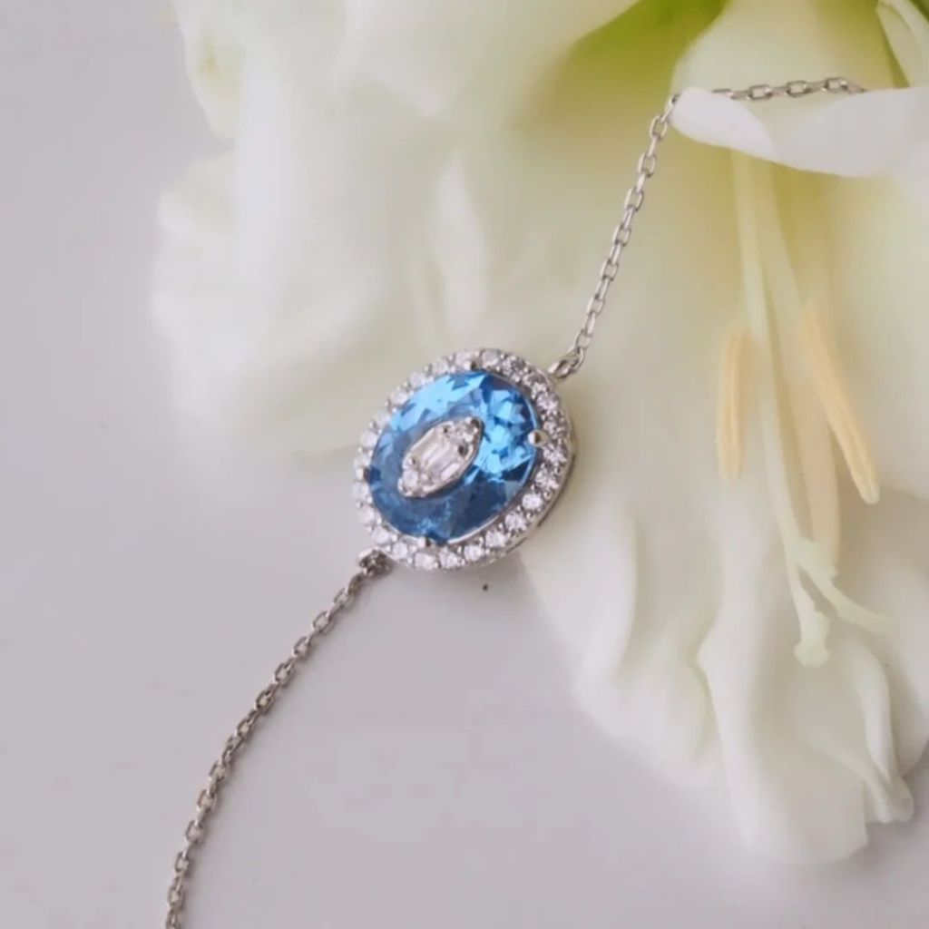 Close-up of a dazzling bracelet featuring a large Cobalt Blue stone surrounded by smaller clear stones, resting on a flower background.