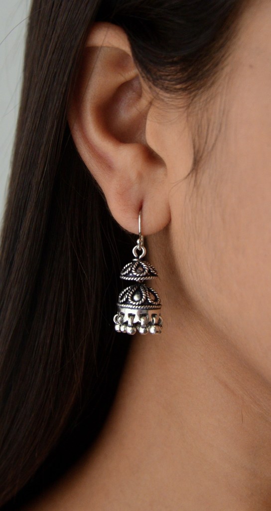 Close-up of a woman wearing a silver jhumka earring featuring intricate design, showcasing elegance and lightweight craftsmanship.