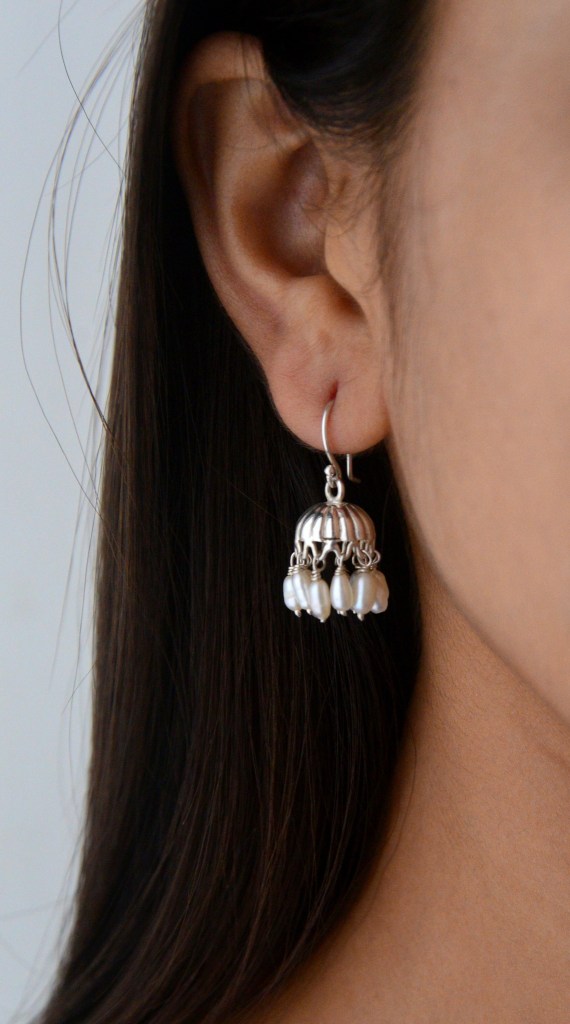 Close-up of a woman wearing a silver chandelier earring with pearls, showcasing the intricate design and elegance.
