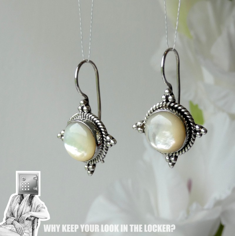 Pair of elegant silver earrings featuring round, iridescent pearls set in ornate designs, displayed against a soft background.