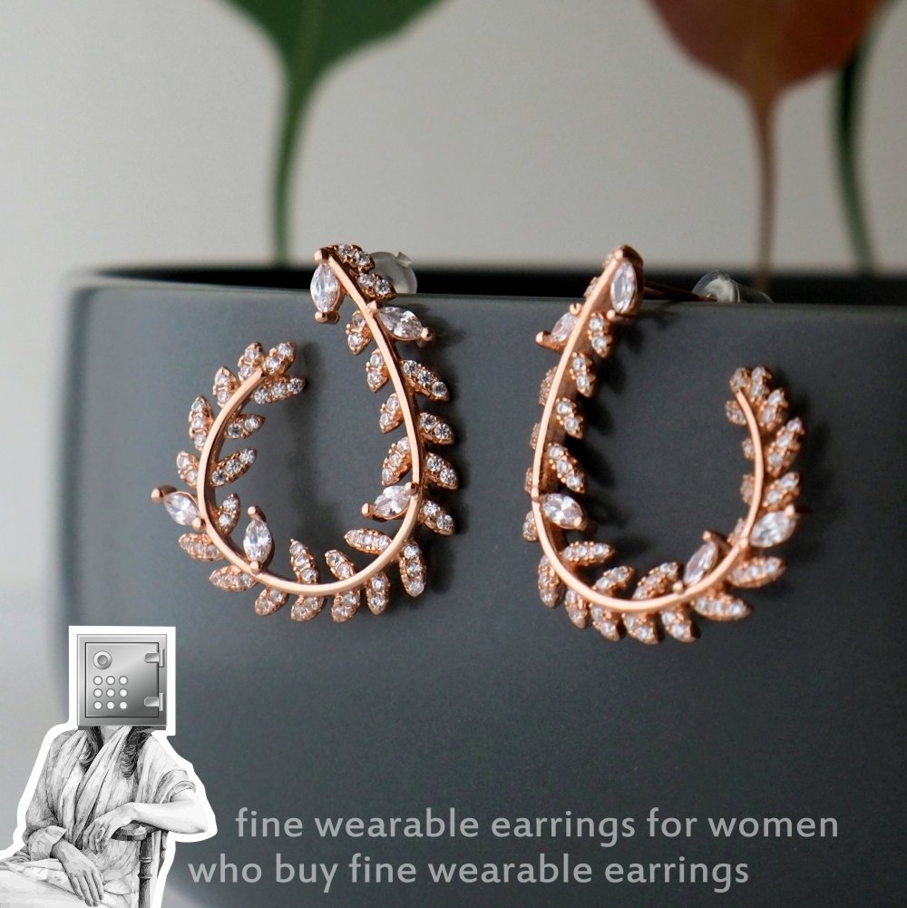 Elegant rose gold earrings in a leaf design adorned with sparkling crystals, displayed against a dark background.