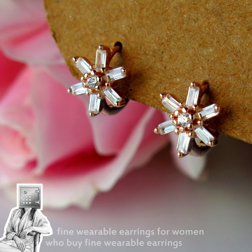 Elegant floral earrings with rose gold and clear crystals, displayed against a soft pink background.