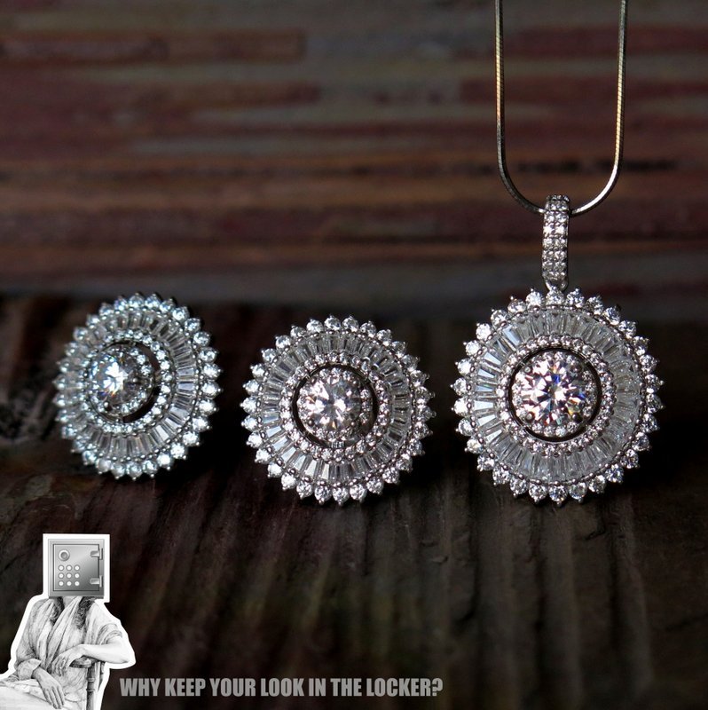 A set of elegant jewelry featuring a pendant and matching earrings, each adorned with intricate diamond-like designs, displayed on a wooden surface.