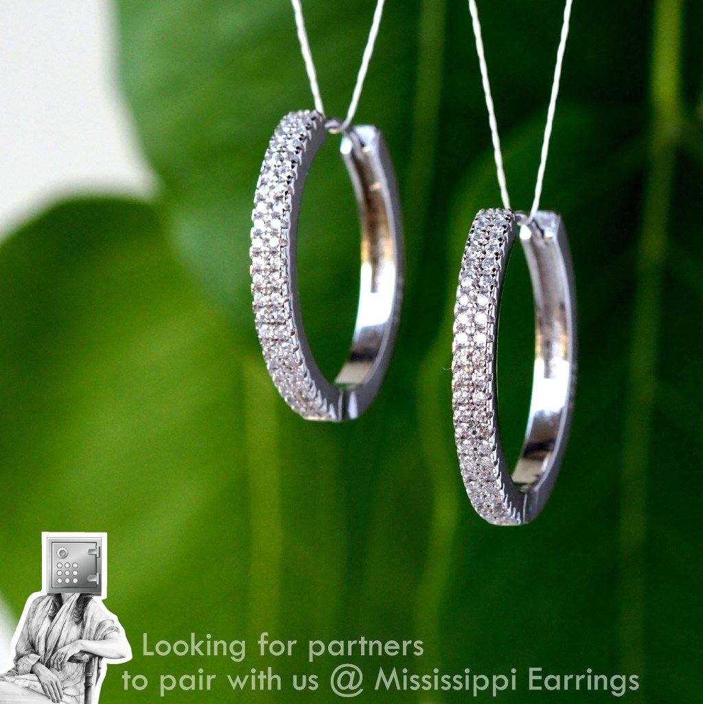 Close-up of sparkling silver hoop earrings hanging against a green leaf background. The earrings feature embedded diamonds along the outer edge.