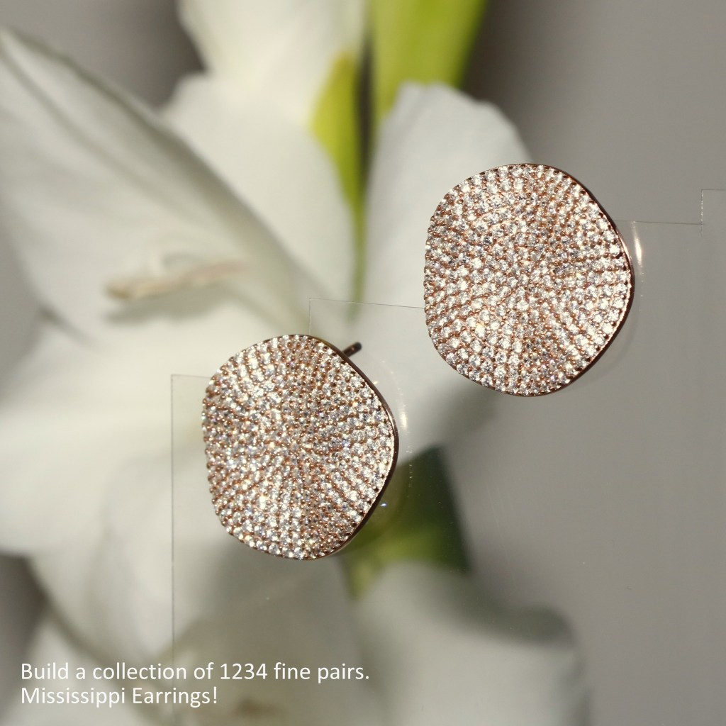 Close-up of a pair of sparkling rose gold earrings with a textured design, displayed against a blurred floral background.